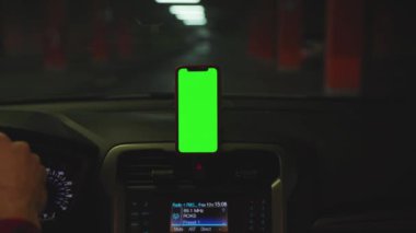 INEW YORK - 5 Nisan 2019: Karanlıkta yakın çekim yapan adam, gösterge panelindeki yeşil ekran ekranlı akıllı telefonu kullanıyor.