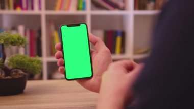 NEW YORK - 19 Mayıs 2019: Masa görevlileri telefonu dikey yeşil ekran kullanımıyla tutun dokunma dijital akıllı telefon ev iletişim teknolojisi internet krom sosyal medya arka plana yavaşça tıklayın