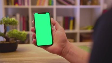 NEW YORK - 19 Mayıs 2019: İnsan elleri telefonu dikey yeşil ekran kullanımıyla tutuyor dokunma dijital akıllı telefon ev iletişim teknolojisi internet Chroma sosyal medya arka plana yavaş çekimde tıklıyor