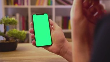 NEW YORK - 19 Mayıs 2019: Dikey yeşil ekranlı genç adam telefonu tut dokunmatik akıllı telefon ev iletişim teknolojisi internet krom sosyal medya arka plan yavaş tıklayın