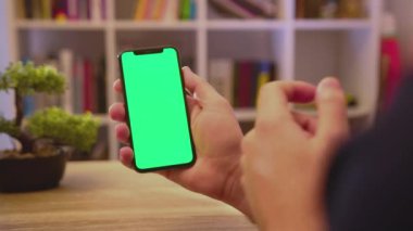 NEW YORK - 19 Mayıs 2019: Dikey yeşil ekranlı genç adam telefonu tut dokunmatik akıllı telefon ev iletişim teknolojisi internet krom sosyal medya arka plan yavaş tıklayın