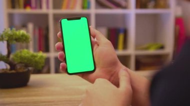 NEW YORK - 19 Mayıs 2019: Dikey yeşil ekran kullanımı ile eller telefonu tutun dokunma dijital akıllı telefon ev iletişim teknolojisi internet Chroma sosyal medya arka plan yavaş çekim tıklayın
