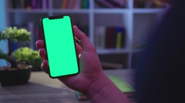 NEW YORK - 19 Mayıs 2019: Geceleyin adam telefonu dikey yeşil ekran kullanımıyla tut dokunma dijital akıllı telefon ev iletişim teknolojisi internet krom sosyal medya arka plan yavaş tıklayın