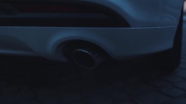 Modern araba egzoz borusundan duman emisyonu. Düşük açılı yeni lüks otomobil egzoz borusu havayı kirletiyor. Araba ayrıntıları.