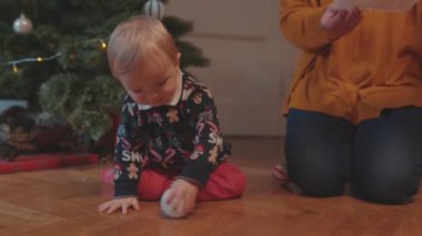 Lviv, Ukrayna - 7 Ocak 2020: Büyükannesiyle Noel oyuncağıyla süslenmiş köknar ağacının yanında oynayan sevimli çocuk. Aile bağı. Kış tatili kavramı.