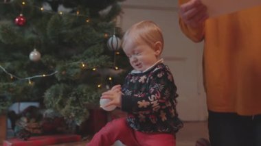 Lviv, Ukrayna - 7 Ocak 2020: Mutlu bir büyükanne olarak küçük torununu evde dekore edilmiş Noel ağacının yanında büyüttü. Aile toplantısı.