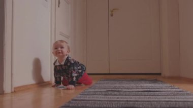 Lviv, Ukrayna - 7 Ocak 2020: Xmas süveter giyen şirin çocuk yerde sürünerek etrafa bakıyor. - Evde. Çocukluk kavramı.