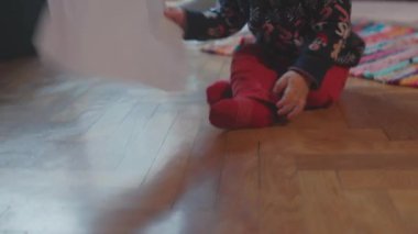 Lviv, Ukrayna - 7 Ocak 2020: Odada yerde sürünen, kağıt sıkan, kameraya bakan, tatil süveteri giyen sevimli bebek. Aile ve çocukluk kavramı.