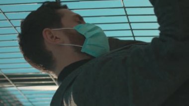 Yüz maskesi takan adam dikey ekranda yavaş çekimde COVID-19 koronavirüs enfeksiyonu salgını salgını salgını salgını salgını salgını salgını salgını için dikey ekran kamerasında bekliyor.
