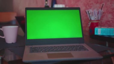 Masadaki dizüstü bilgisayarın üzerinde yeşil ekranlı ev içi iletişim defteri internet tablosu teknolojisi monitörü klavye kahvesi yavaş çekim çevrimiçi.
