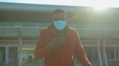 COVID-19 Coronavirus enfeksiyonu Koruyucu Yüz Maskesi takan Afrikalı Amerikalı adam havaalanı salgını salgını virüsü erkek turist hava hastalığı ağır çekim hastalığı