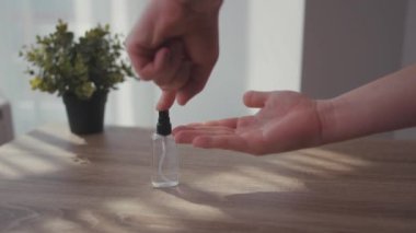 Güneş ışığındaki adam ellerini yıkamak için şeker ve sıvı antiseptik ver. Evde kal Coronavirus COVID19 salgını. Masa enfeksiyonunu dezenfekte et.