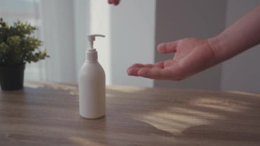 Evdeki adam ellerini yıkamak için ilaç ve sıvı antiseptik veriyor. Evde kal Coronavirus COVID19 salgını. Masa enfeksiyonunu dezenfekte et.