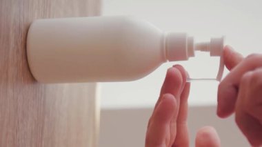 Adam prezervatifi kapat ve ellerini yıkamak için sıvı antiseptik ver. Evde dikey ekran Coronavirus COVID19 pandemiği. Enfeksiyonu dezenfekte et.