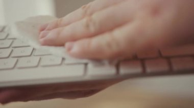 Erkek eli, beyaz bilgisayar klavyesini ıslak mendillerle dezenfekte ediyor. Ev temizliği. COVID-19 Coronavirüs Önleme.