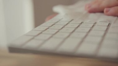 Coronavirus dezenfeksiyonu. Beyaz klavyesini antibakteriyel mendil dezenfektanı ile temizleyen adama yakın çekim. Salgının yayılmasını durdurun. COVID-19.