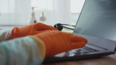 Dünya salgını. Evden çalışan insanlar. Coronavirus karantinası. Yan görünüşlü koruyucu eldiven giyen kişi odada dizüstü bilgisayarı kullanarak interneti tarıyor..