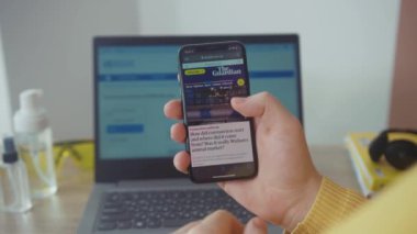 NEW YORK - 28 Mart 2020: Evde genç bir öğrenci akıllı telefonda Coronavirus 'un evde kaldığına dair yeni bir makale okuyor. Salgın, tecrit süresi. Bağımsız, teknoloji.