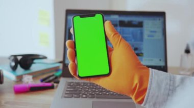 NEW YORK - 28 Mart 2020: İşyeri dizüstü bilgisayarında dikey akıllı telefon uygulaması kullanan yakın plan kişi. Evden çalışıyorum. Sosyal medya. İş için. Sağlık hizmetleri.