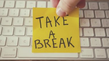 Biraz ara ver. Adam beyaz klavyeye dostane bir etiket yapıştırıp işten izin istiyor. Rahatlama konsepti. Yakın çekim..