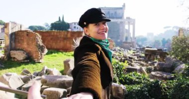 ROME, ITALY - 19 Mayıs 2017: Avrupa Şehri arka planında elini sallayan bir adama yol gösteren sevimli genç kadını takip et antik bir anıt Avrupa romantik kız arkadaş macerası turizmi