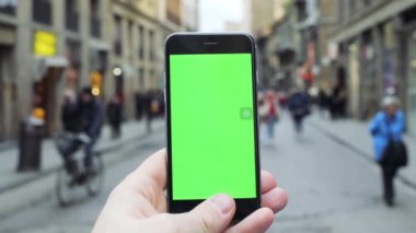 FLORENCE, ITALY - 4 APRIL 2017: Kapatın adam telefonu dikey yeşil ekran arka planlı şehir sokak iletişimi internet bulanık akıllı telefon mesajı mobil mimarisi