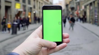 FLORENCE, ITALY - 4 APRIL 2017: Kapatın el kamerasını dikey yeşil ekran arka planı olan insanlar şehir sokak iletişimi internet bulanık akıllı telefon mesajı mobil mimarisi