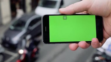 FLORENCE, ITALY - 4 APRIL 2017: Yatay yeşil ekranlı telefonu kapat arka plandaki insanlarla el ele tut şehir sokak iletişimi internet bulanık akıllı telefon parmak mesajı mimarisi