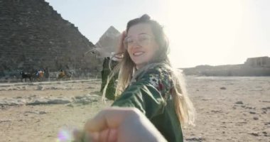 CAIRO, EGYPT - 5 Ocak 2017: Beni takip edin, güzel, genç bir kadın, Mısır 'da mutlu bir gülümsemeye sahip, gülümseyen bir adama önderlik ediyor, Mısır' da kahire 'li çift, antik hayvan eğlence dünyası giza piramit turizmi.