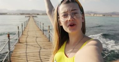 Gözlüklü güzel genç bir kadın el sallıyor gülümsüyor konuşuyor Mısır 'da denizde mutlu hissediyor sevgi dolu bir kız çift doğa güneşi Afrika selfie seyahati tatil aktivitesi arıyor