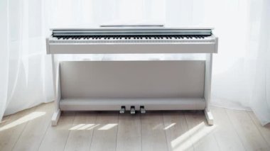 Beyaz Piyano pencere kenarında duruyor. Ev müziği hafif. Güneşli, zengin, akustik enstrüman.