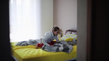 Uzun saçlı çekici genç kız lüks bir dairede yatakta eğleniyor mutlu çocuk partisi kızı ev dansı teknolojisi yavaş çekim portresi.