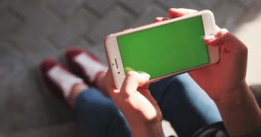 NEW YORK - 5 Nisan 2018: Elinde beyaz telefon tutan ellerini kapat yatay yeşil ekran kullan meşgul sokak kaydırma sayfalarında otur internet teknolojisi akıllı telefon mesajı cep telefonunu arakla