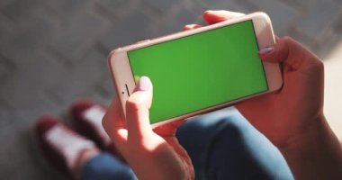 NEW YORK - 5 Nisan 2018: Elinde beyaz telefon tutan ellerini kapat yatay yeşil ekran kullan meşgul sokak kaydırma sayfalarında otur internet teknolojisi akıllı telefon mesajı cep telefonunu arakla