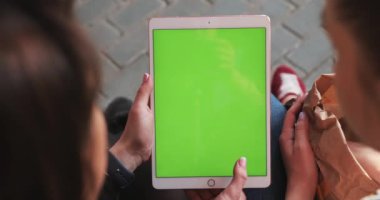 NEW YORK - 5 Nisan 2018: İki kadın, yeşil ekranlı tablete bakıp alışveriş teknolojisi krom anahtar dokunuşlu elektronik taşınabilir ipad görüntüleme cihazı kullanıyor