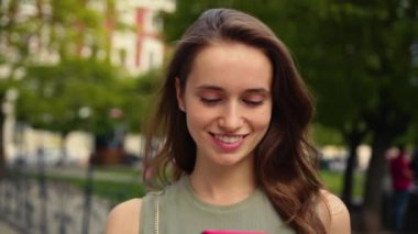 Çekici, güler yüzlü, parlak günışığında genç bir kadın şehir merkezinde kırmızı telefon yürüyüşü yapıyor. Yaz mevsiminde internet sektörüne göz gezdirme teknolojisi dışında gezdirme aracı mobil sokak mutlu portresi.