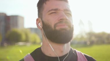 Portre yakışıklı genç sporcu kameraya bak. Spor kıyafetleri giymiş gülümsüyor. Dışarıda koşuyor.