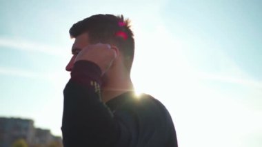 Portre yakışıklı genç sporcu kulaklık takıyor. Spor kıyafetleri giyiyor. Dışarıda koşuyor.