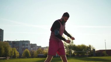 Yakışıklı genç sporcu spor yapıyor spor kıyafetleri giyiyor dışarıda koşuyor müzik dinliyor günbatımında spor yapıyor spor yapıyor dışarıda antreman yapıyor internette doğa çimleri.