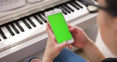 Tokio, Japonya - 7 Nisan 2018. Akıllı telefon kullanan, dikey yeşil ekran arka plan piyano kromakey beyaz dijital cihaz zengin avuçlarını modern yaşam tarzına uygun hale getiriyor.