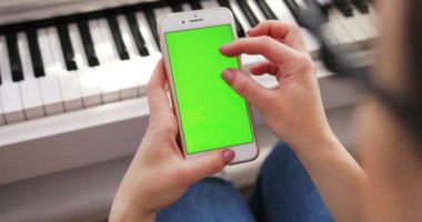 Tokio, Japonya - 7 Nisan 2018.Elde tutulan genç kadın dikey yeşil ekran arka plan piyano kromakey beyaz dijital cihaz zengin yaşam tarzı modern teknoloji dinlenme tesisi