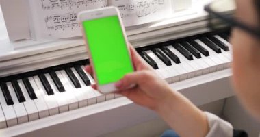 Tokio, Japonya - 7 Nisan 2018. Elinde dikey yeşil ekran arka plan piyano kromakey beyaz dijital cihaz ile akıllı telefon tutan genç kadın avuçlarında zengin yaşam tarzı modern teknoloji tesisi kuruyor.