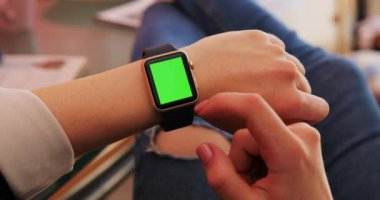 Kadın el hareketleriyle modern bir akıllı saat kullanımını gösteriyor. Mutfaktaki yeşil ekranlı ev yapımı spor arka plan bilgisi. Moda tasarımcısı kız internet mesajları teknolojisi yakın durun.