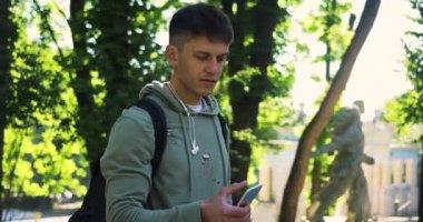 Genç adam telefon kulübesini şehir sokaklarında kullanıyor mutlu günbatımı günbatımı internet yüz teknolojisi mesajları yakışıklı, çekici erkek akıllı telefon mesajları dışarıda, yakın plan portresi.