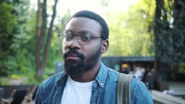 Ciddi bir portre. Gözlüklü genç Afro-Amerikalı. Sokak güneşinde kameraya bak. Teknoloji mesajı.