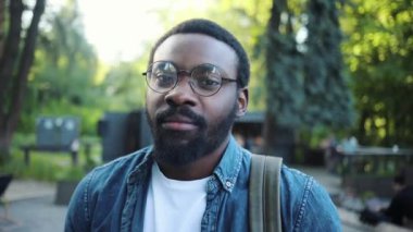 Sakallı Amerikalı genç bir adamın portresi kameraya bakıp gülümsüyor. Afro mutluluğu yakından takip ediyor. Moda insanları yakışıklı, çekici, yavaş çekim kentsel kentsel manzarayla yüzleştiriyor.