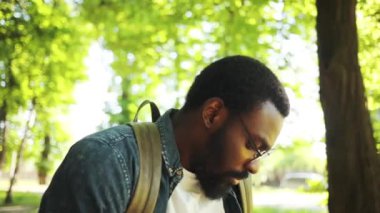 Ciddi yüzlü Afro-Amerikalı, gözlüklü, telefon kullanan, gün batımında sokakta yürüyen, güneş ışığı alan, cep telefonu kullanan, teknoloji işadamlarının dışında moda interneti olan, siyahi şehir gezgini.