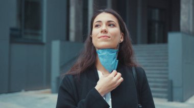 Kafkasyalı mutlu bir ofis kadını yüz maskesi korumasını kaldırıyor ve kameraya gülümseyen temiz havanın tadını çıkarıyor. Salgın sona erdi. Kadın portreleri..