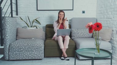 Mutlu genç kadın internet haberlerini öğrenirken alkış tutuyor. Hoş, neşeli genç iş kadını, dizüstü bilgisayarda klavyeyi nasıl yazacağını göstermek için davet ediyor..