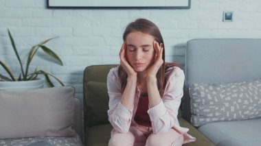 Kafkasyalı genç kadın evde dizüstü bilgisayarla çalışırken, şakak başı masajı yaparken ve ara verirken çok kötü baş ağrısı çekiyor. Çok çalışıyorum. İşkolik konsept.